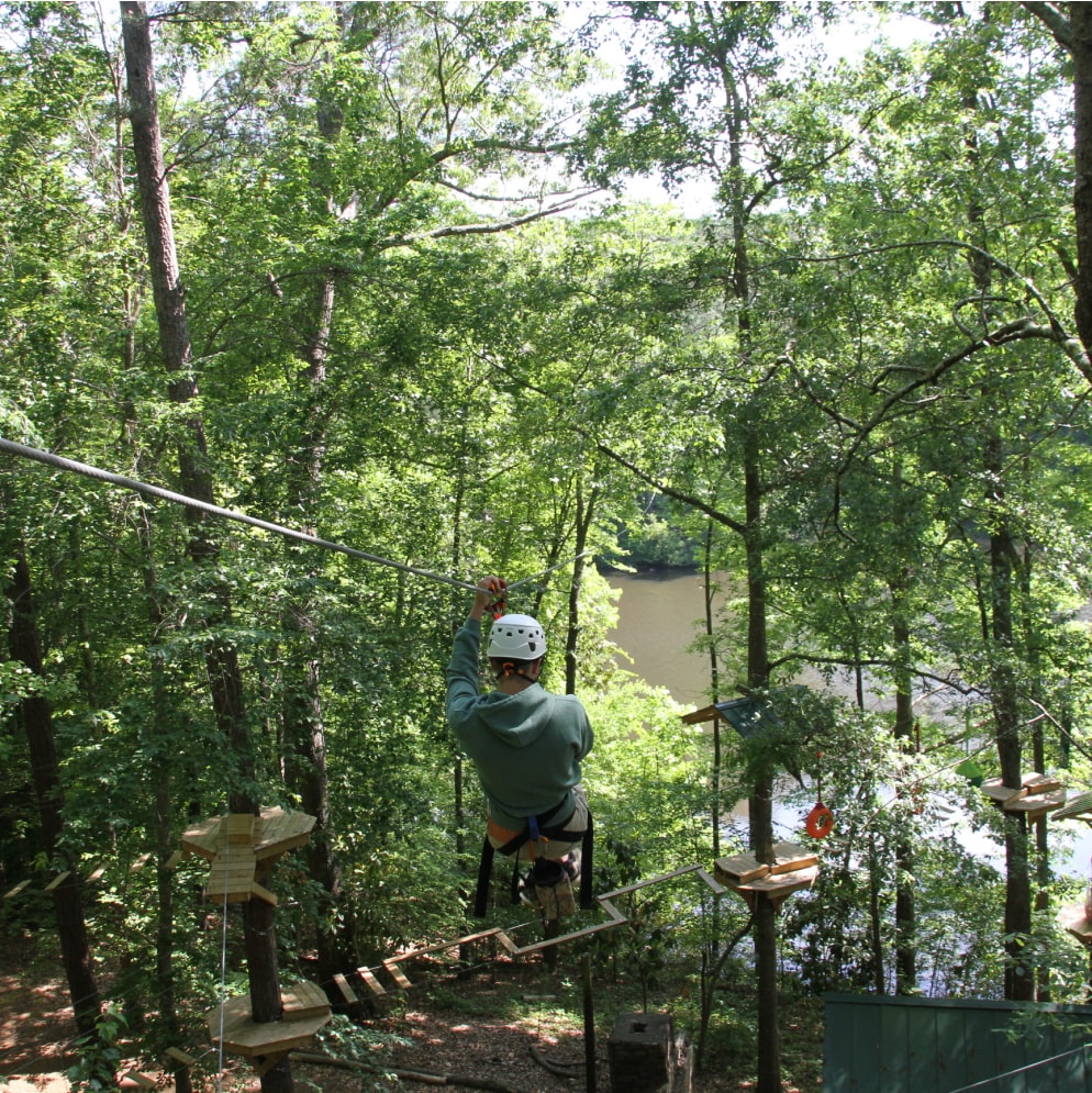 man ziplining through adventure course at nature center chattaahoochee